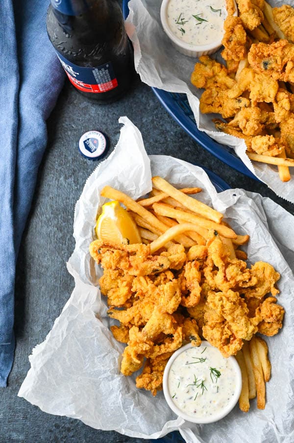 Serving fried whole belly clams with french fries, tartar sauce and lemon.