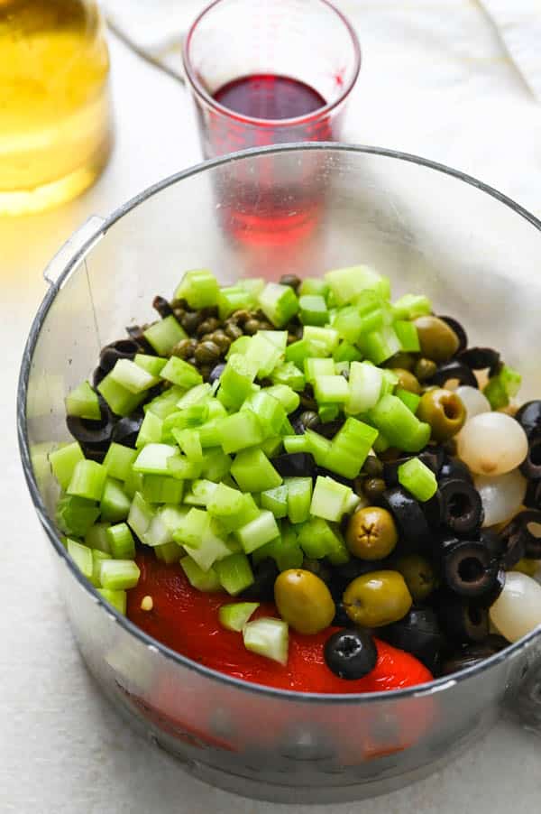 adding ingredients to the food processor for muffuletta olive salad.