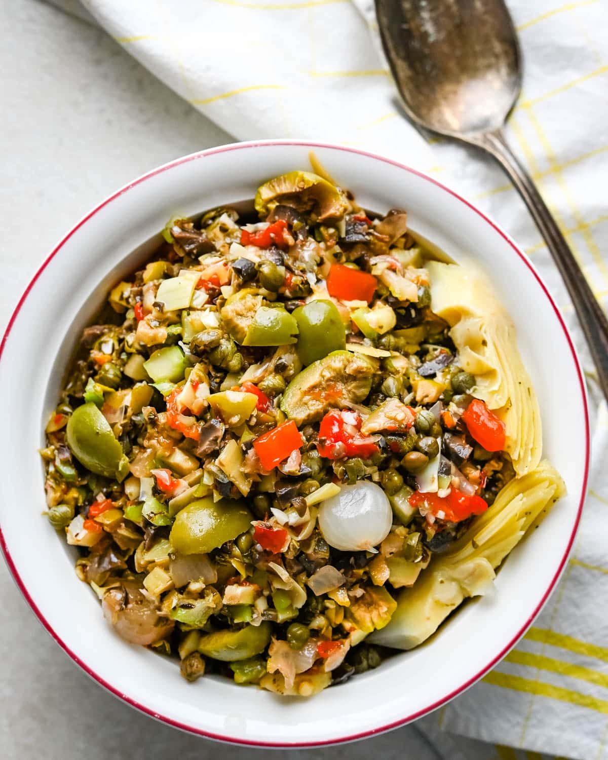 Serving a dish of muffuletta olive salad in a white bowl.