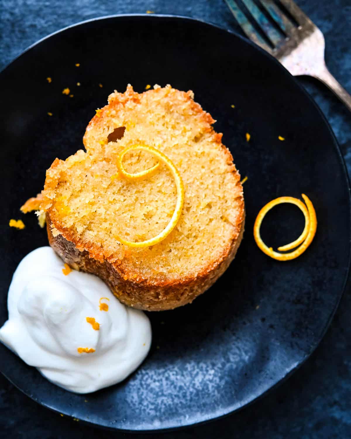 A slice of whiskey cake with orange peel and whipped cream.