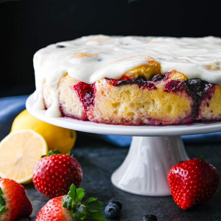 A pedestal cake plate with sweet glazed berry sweet rolls.