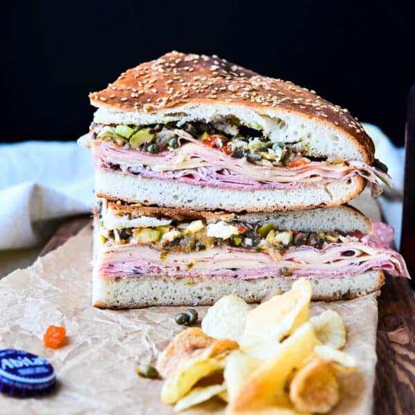 a muffuletta sandwich stacked on itself with a pile of chips and an Abita beer.