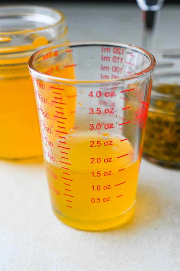 measuring passion fruit syrup into a glass measure.