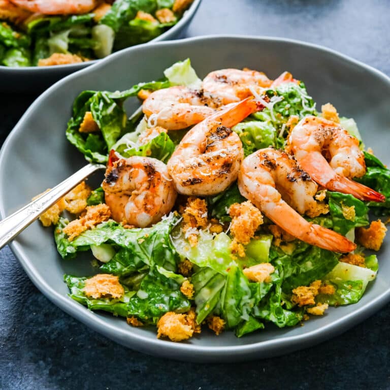 A grilled shrimp caesar salad in a shallow bowl.
