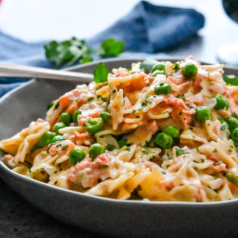 A dish of smoked salmon pasta with peas and cream sauce.