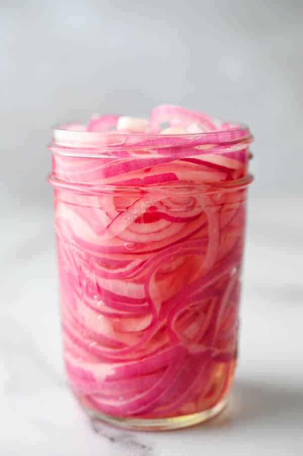 layers of tart sweet pickled onions in a jar.