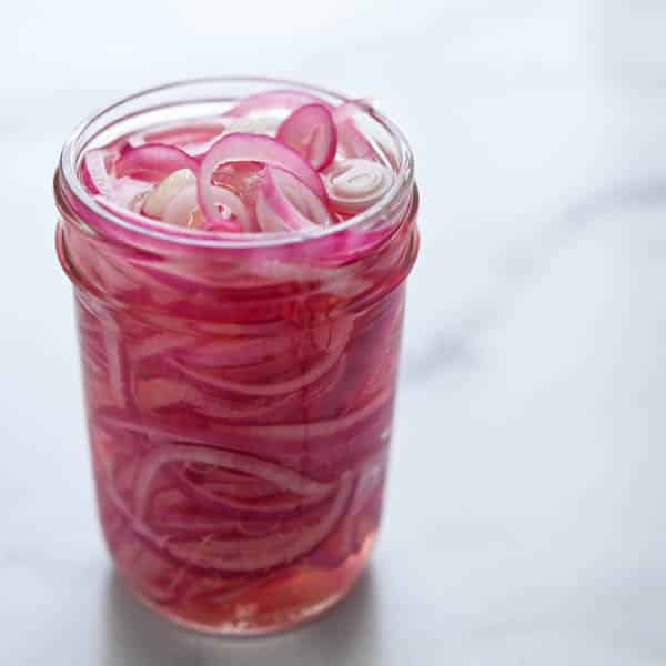 pink pickled onions in a jar.