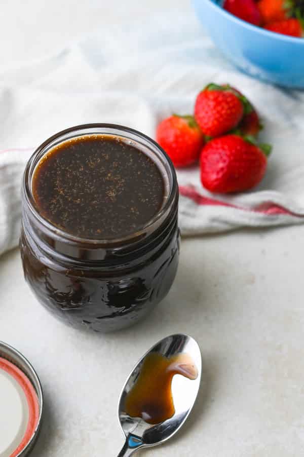 Dessert sauce in a jar with a bowl of berries.
