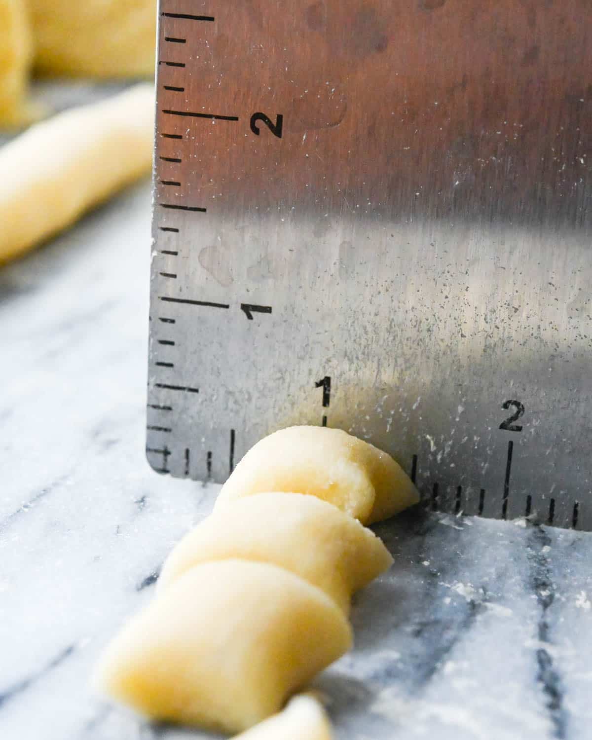 I am using a dough scraper to cut 1" bites of homemade gnocchi.
