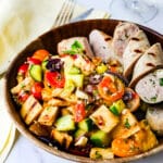 A bowl of panzanella with grilled chicken sausages.