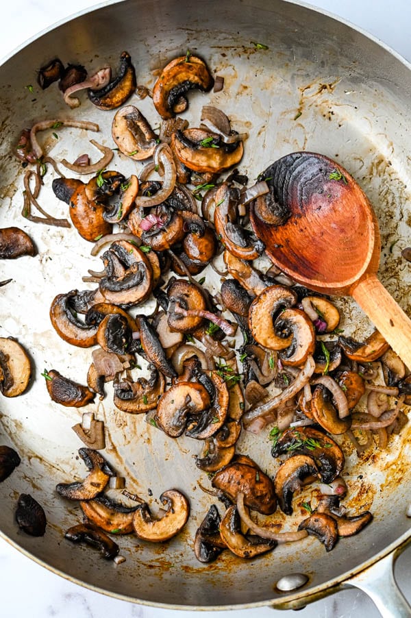 sautéing mushrooms and shallots with thyme in a saute pan.
