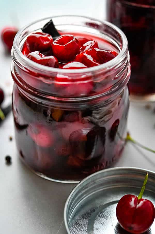 Pickled fruit and vanilla bean in a glass jar.