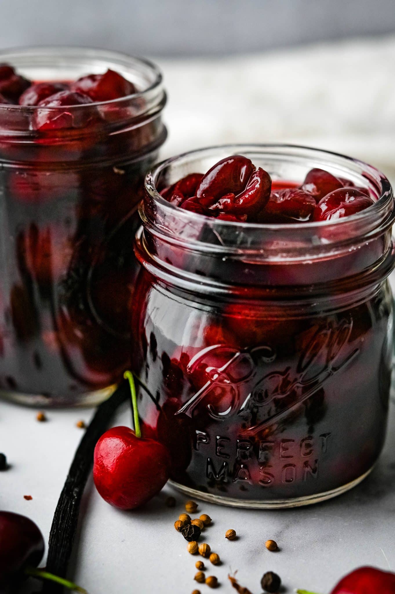 transferring pickled cherries to glass mason jars.