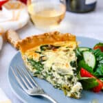 A slice of spinach goat cheese quiche with a side salad.