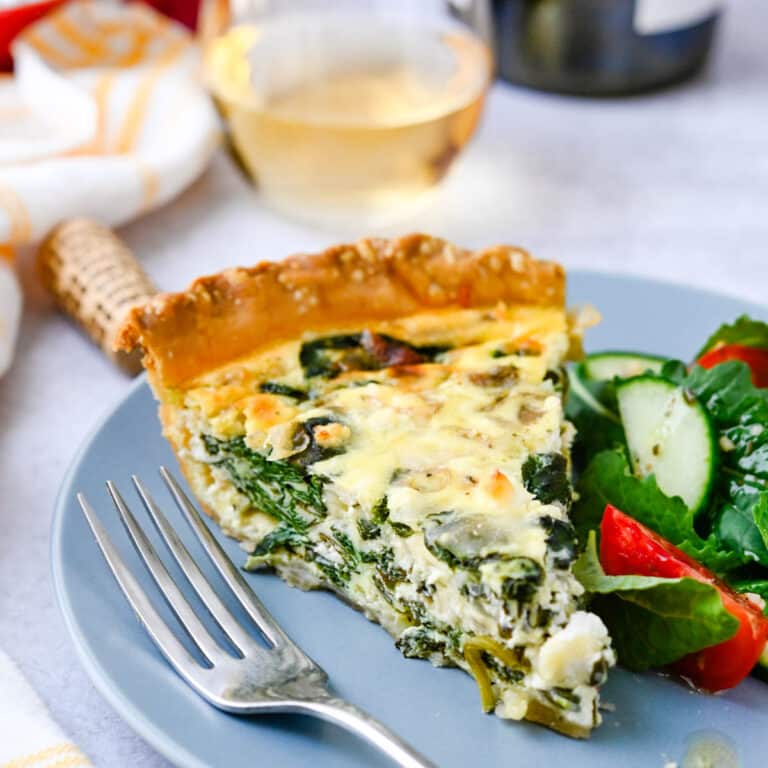 A slice of spinach goat cheese quiche with a side salad.