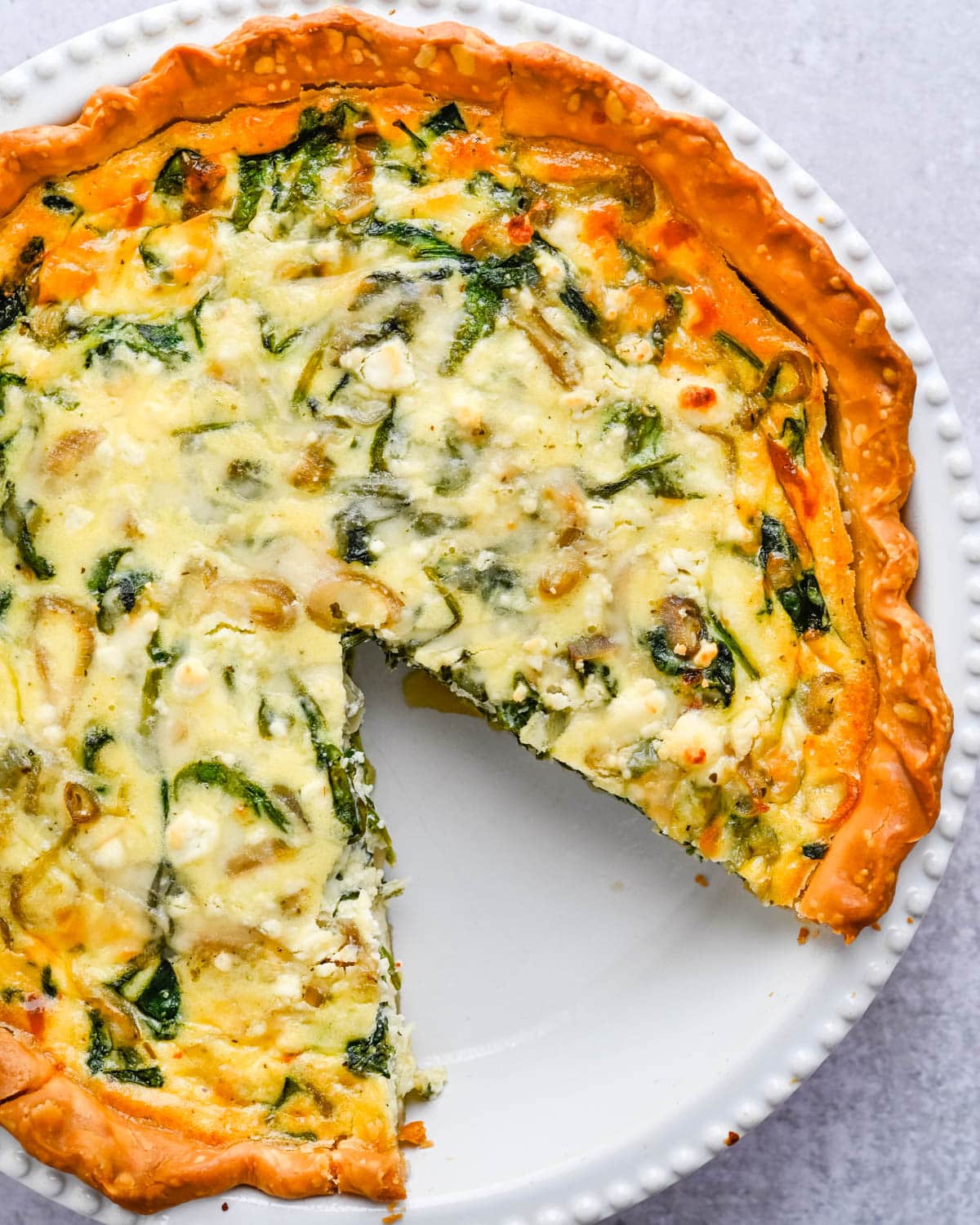 Spinach goat cheese quiche in a baking dish.