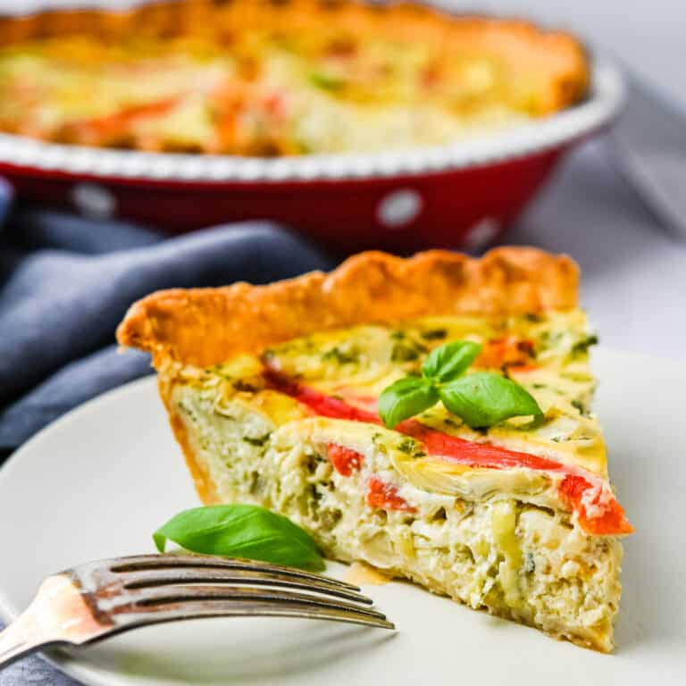 roasted bell pepper artichoke quiche on a plate with a fork.