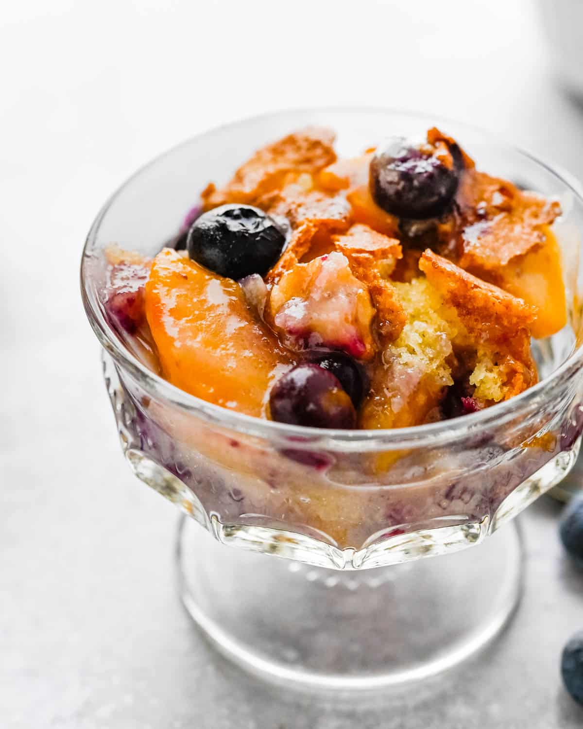 Peach Blueberry cobbler in a footed dish.