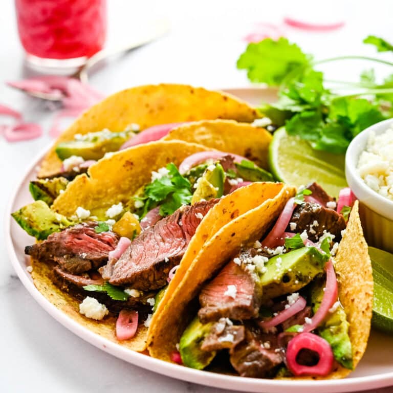 A platter of carne asada tacos with pickled onions.