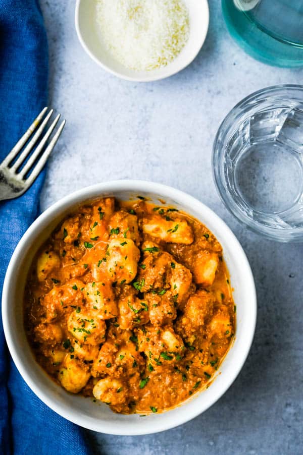 a bowl of gnocchi bolognese with parmesan cheese.