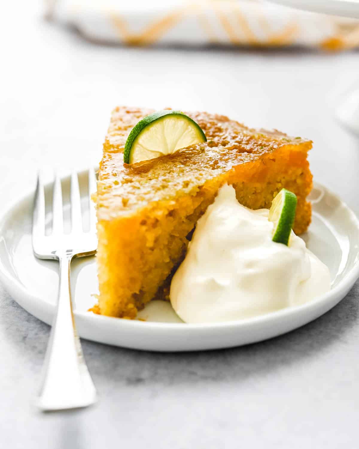 A slice of mango cake with a dollop of whipped cream.