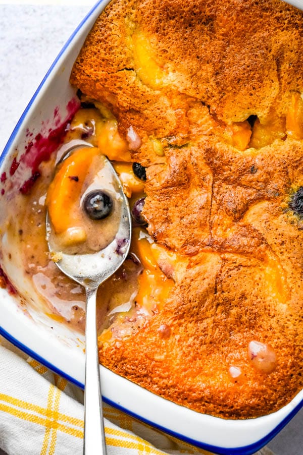 old fashioned peach cobbler with a spoonful missing from the casserole.