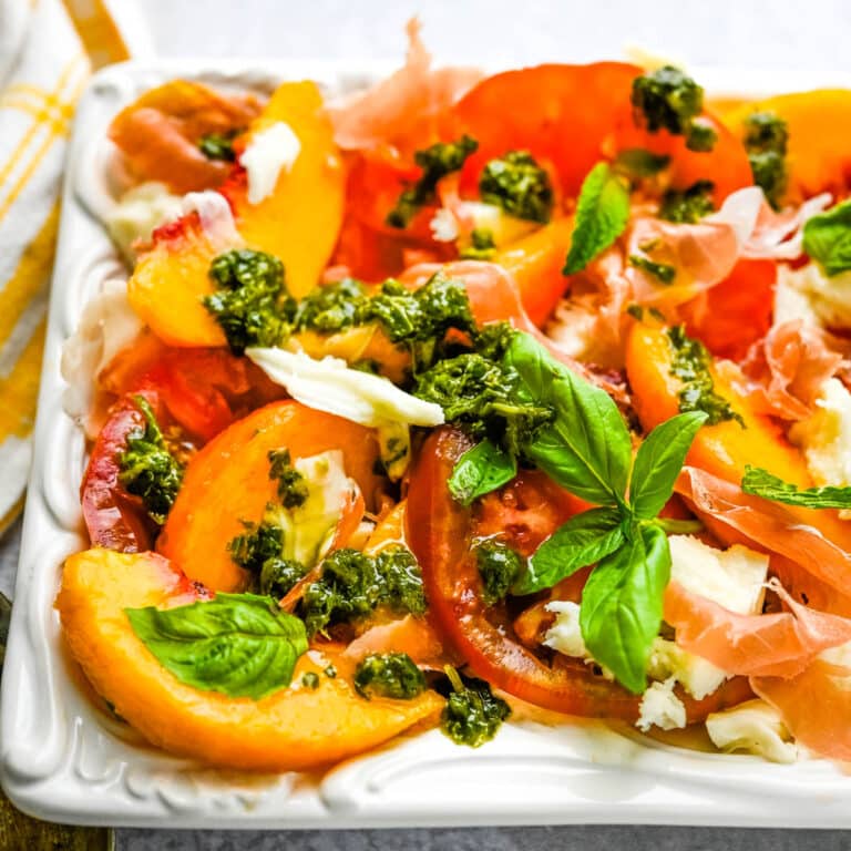 Tomato peach caprese with herb sauce on a platter.