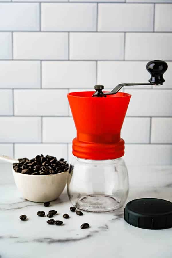filling manual coffee grinder with coffee beans.