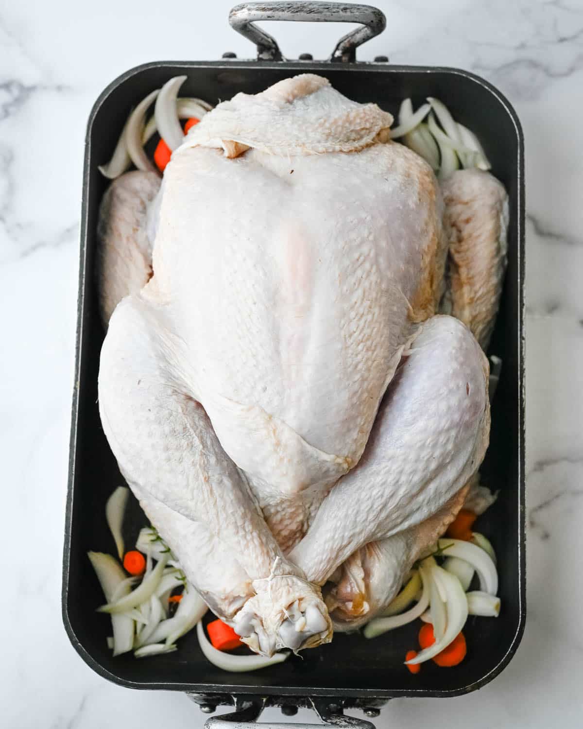 Arranging the brined turkey over a bed of aromatic vegetables.