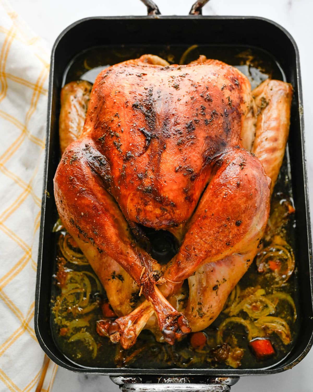 The roasted turkey in the roasting pan with vegetables. 