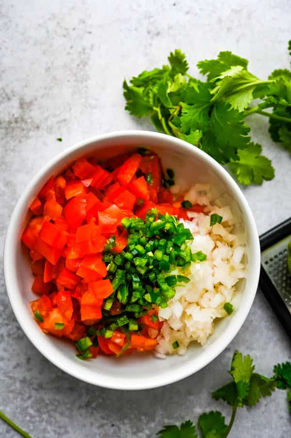 Adding minced peppers to the authentic pico de gallo.