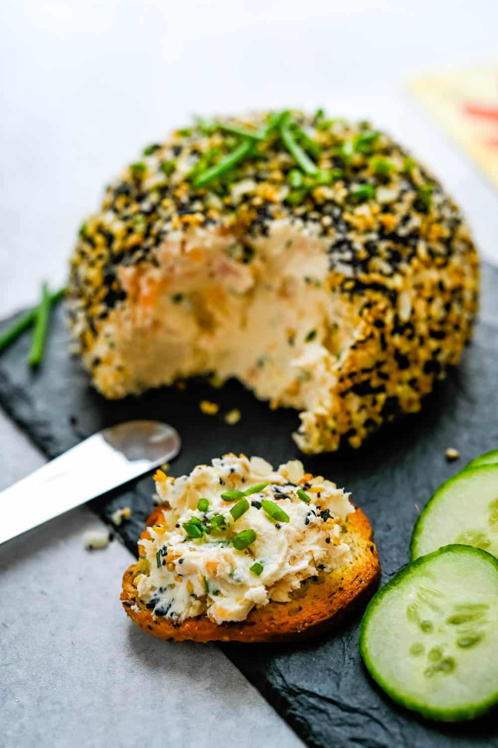 smearing smoked salmon cream cheese ball on a toasted bagel chip.