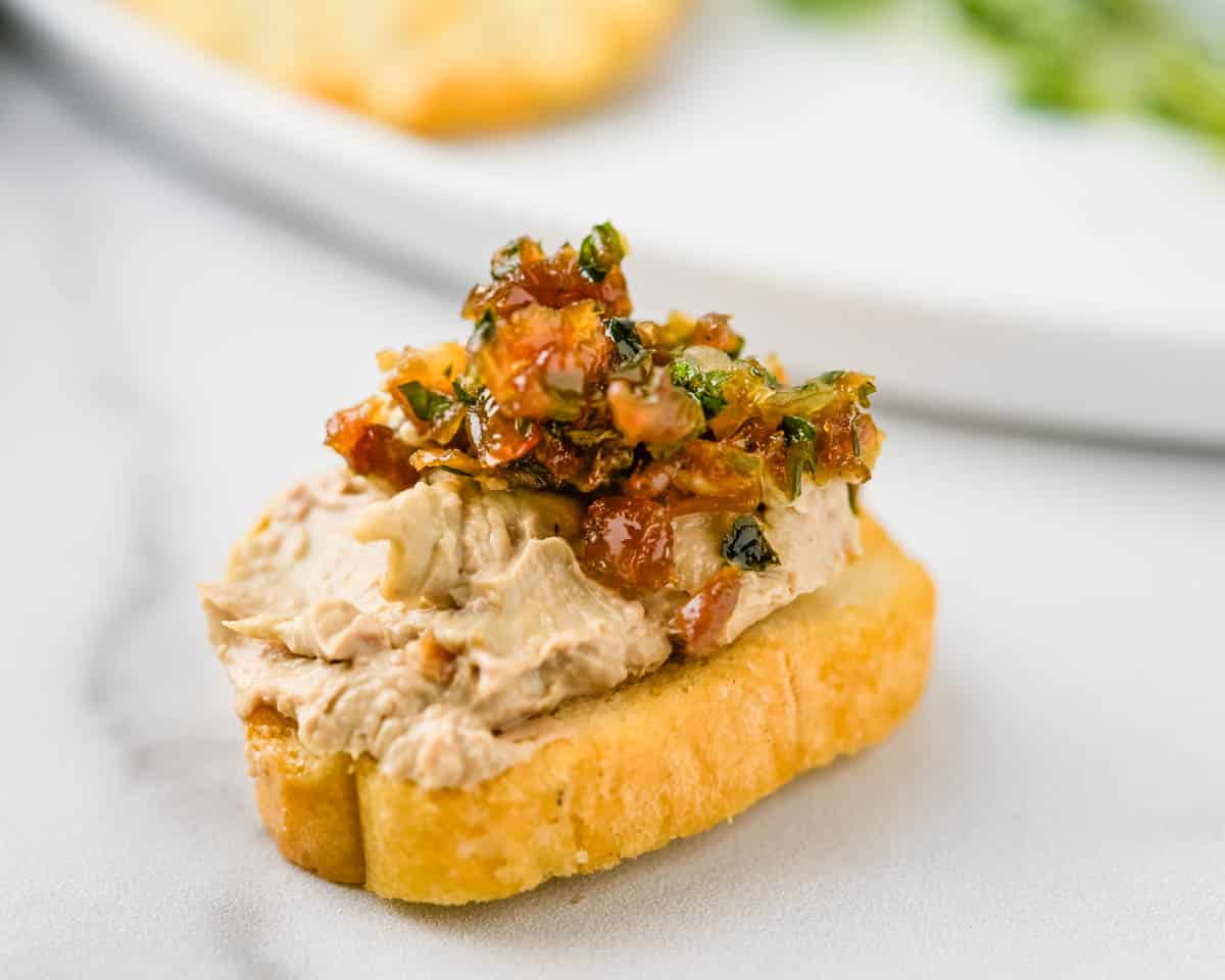 Serving chicken liver mousse on a crostini.