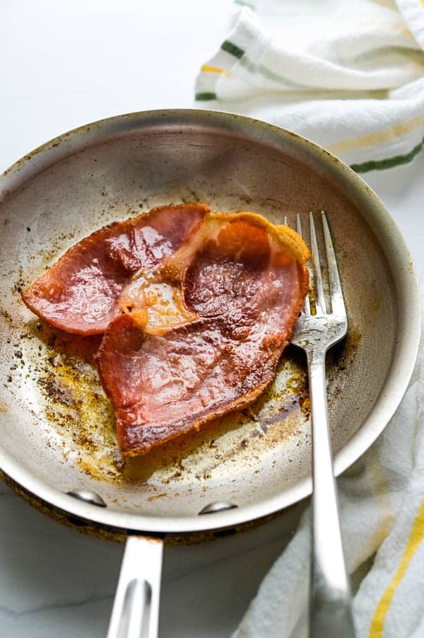 Fried country ham in a skillet.
