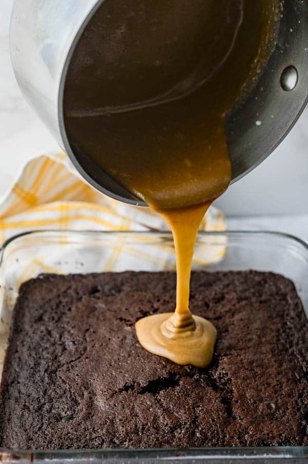 pouring maple glaze over chocolate snack cake.