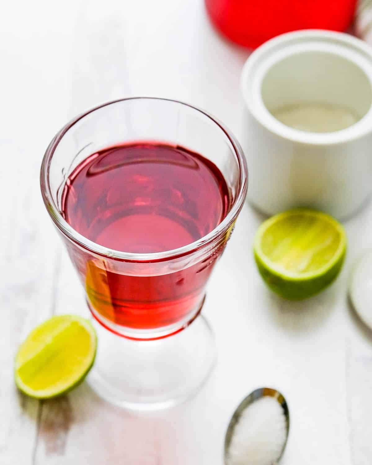 A glass of hibiscus tea with lime and sugar.