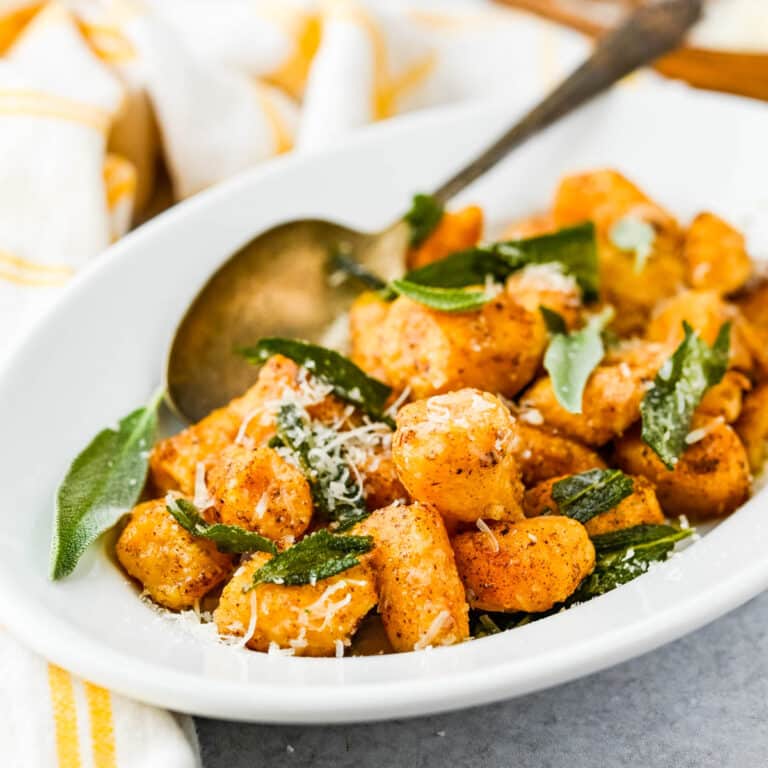 Serving sweet potato gnocchi and sage on a white serving dish.