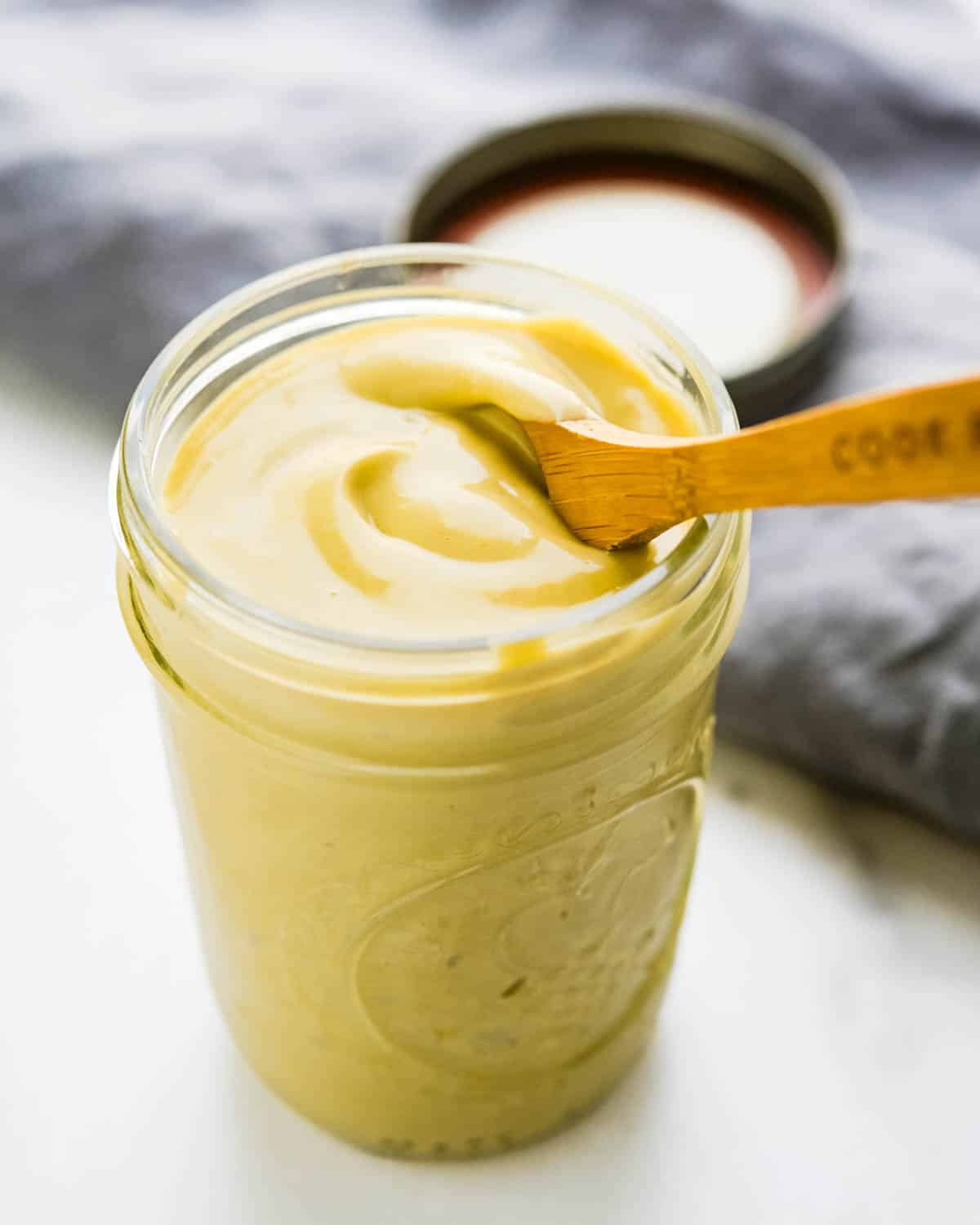 a jar of creamy anchovy vinaigrette with a spoon.