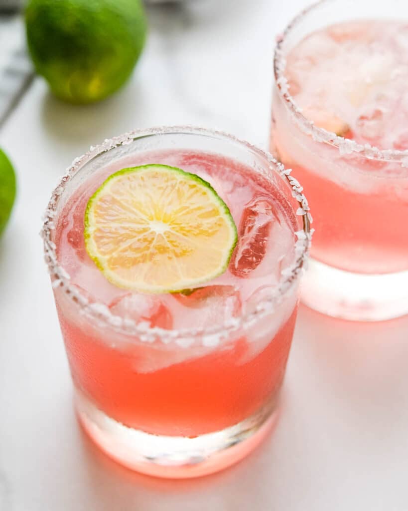 Two glasses of hibiscus margaritas on the rocks.