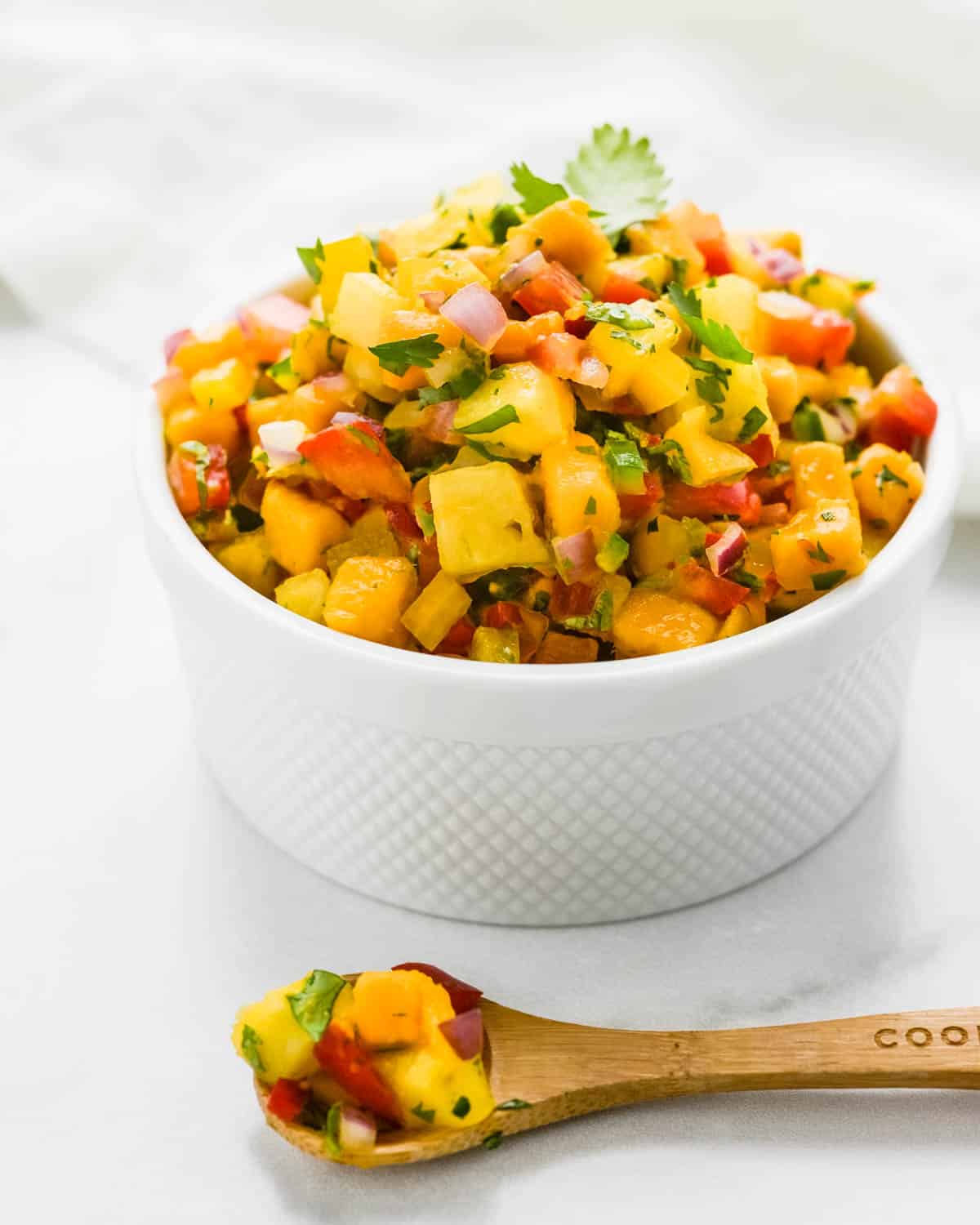 a white dish filled with pineapple mango salsa.