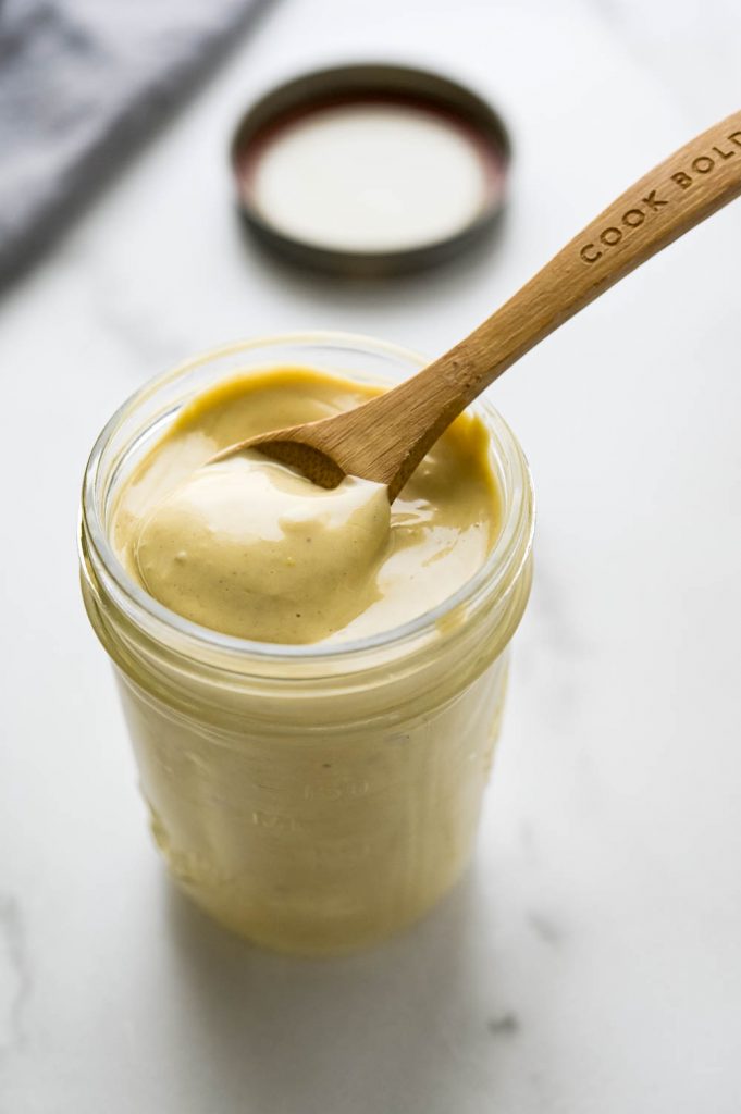 Creamy anchovy vinaigrette in a jar with a spoon.