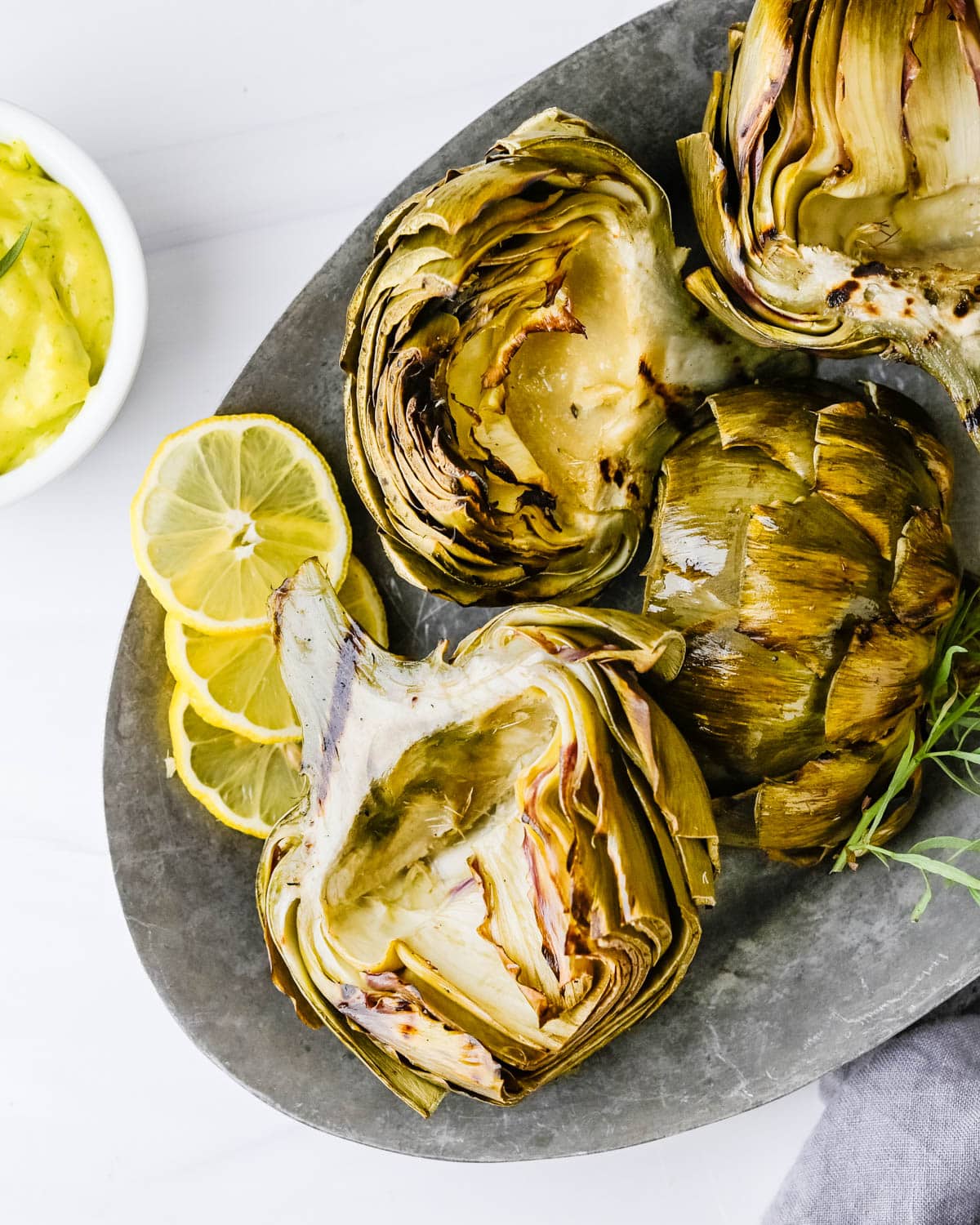 Grilled artichokes on a pewter platter.