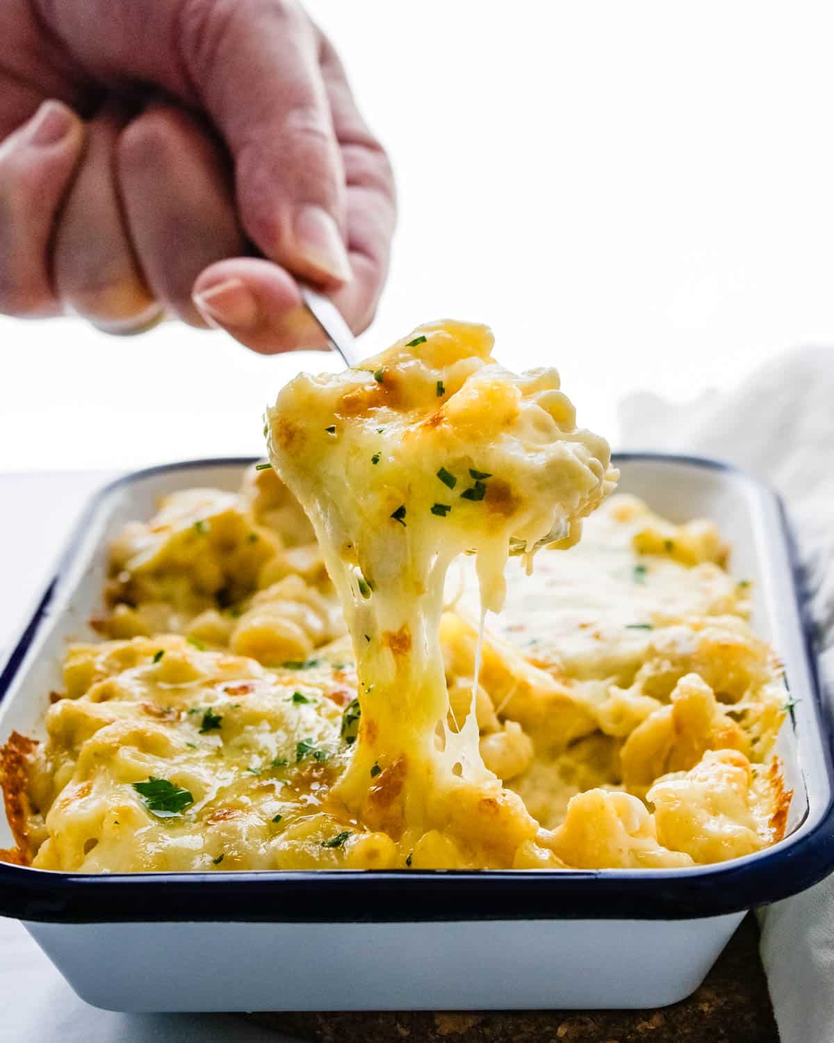 Scooping the ultimate mac and cheese from the casserole dish.