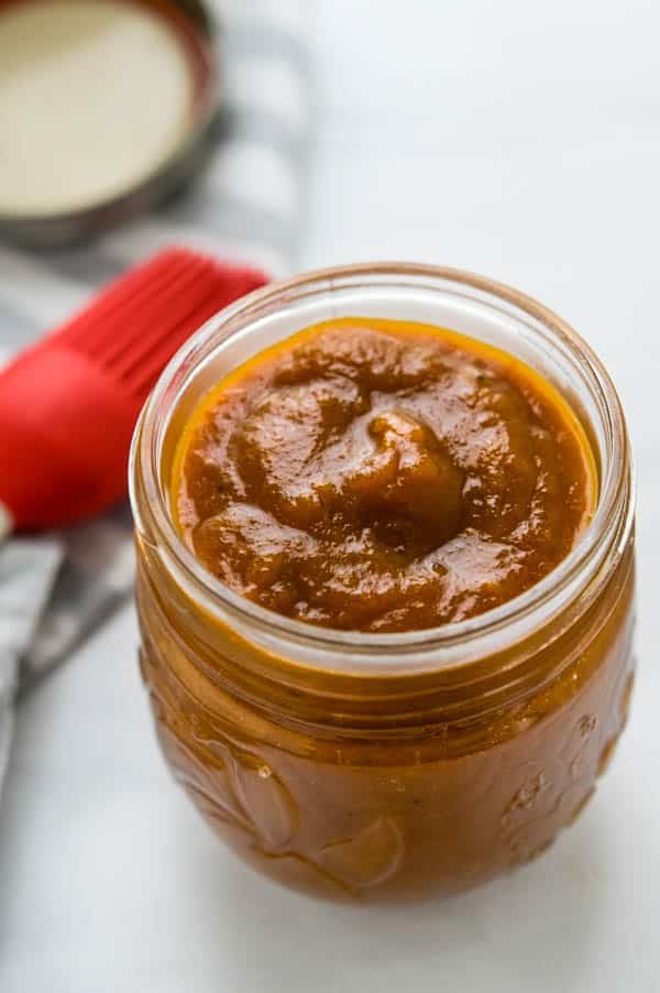 A jar of pineapple bbq sauce with a silicone basting brush. 