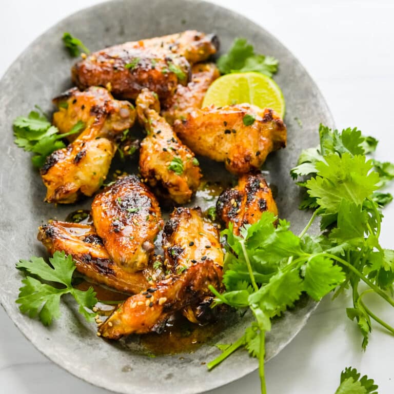 Asian wings on a platter with cilantro and lime.