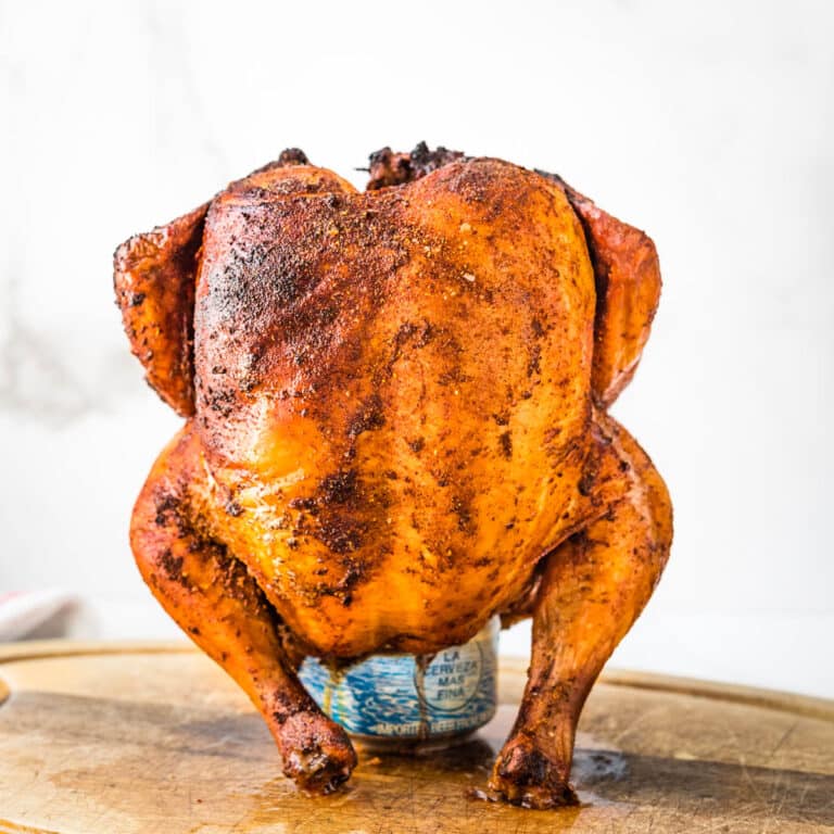A beer can chicken resting on a cutting board.