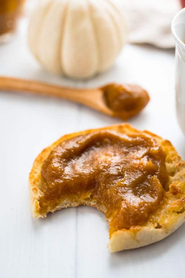 An english muffin topped with homemade pumpkin apple spread and a bite taken out.