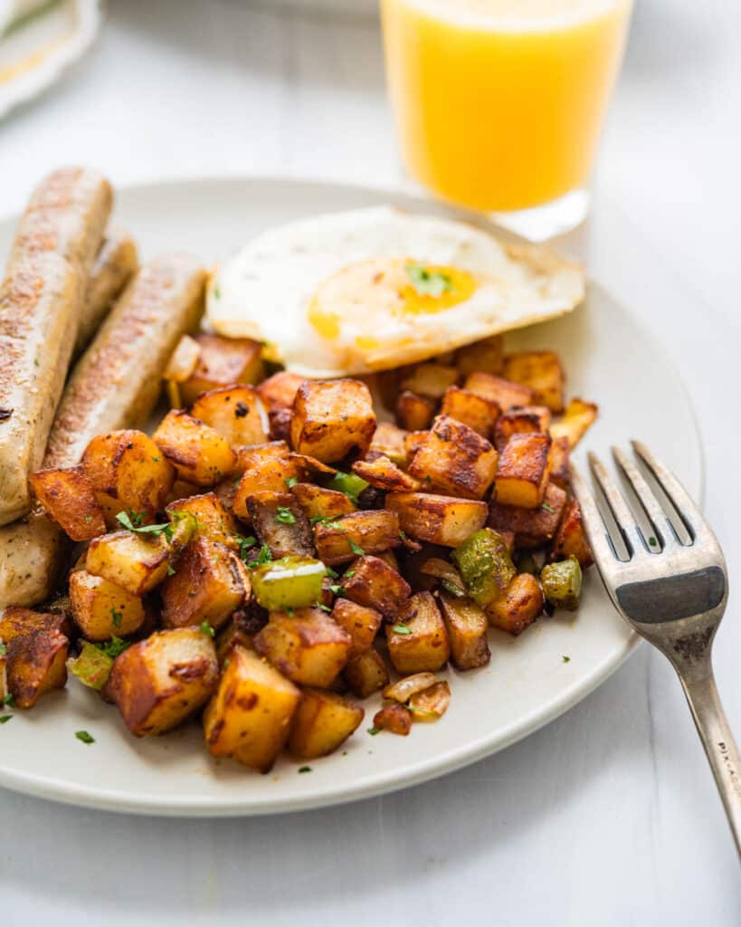 Breakfast potatoes served with eggs and sausage links.