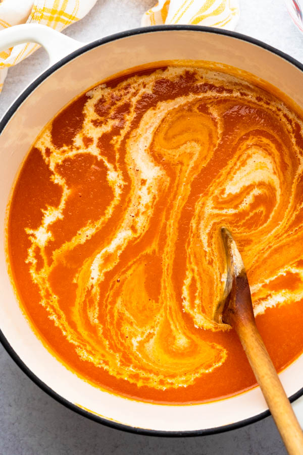 Stirring cream into roasted red pepper tomato soup.