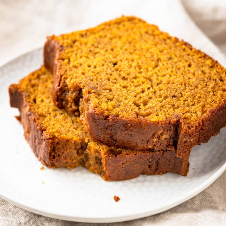 Two slices of pumpkin bread stacked on a white plate.
